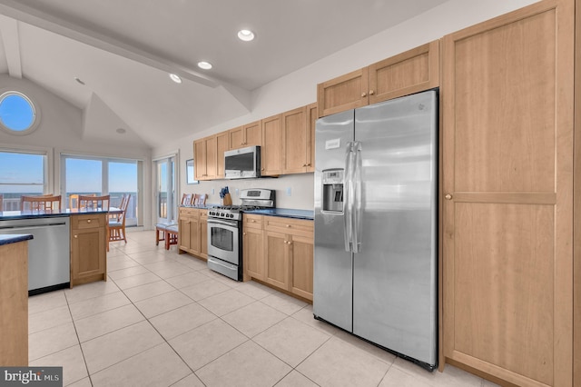 kitchen featuring light brown cabinetry, lofted ceiling with beams, stainless steel appliances, and light tile patterned floors