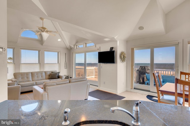 tiled living room featuring vaulted ceiling with beams, ceiling fan, and sink