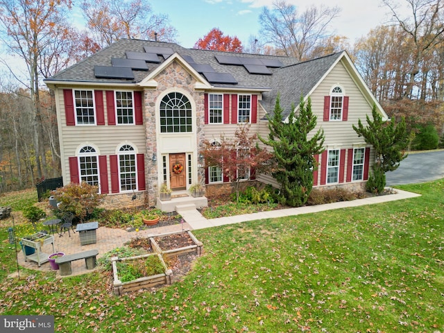 colonial home featuring solar panels and a front yard