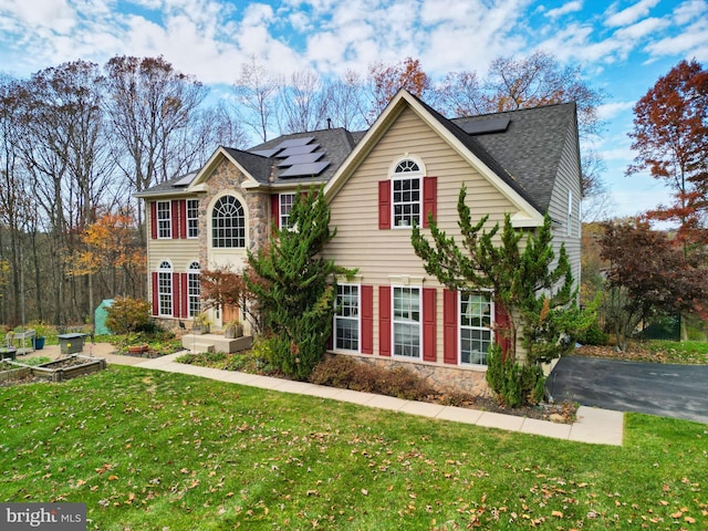 view of front of property featuring solar panels and a front yard