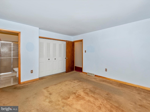 unfurnished bedroom with carpet flooring, connected bathroom, and a closet