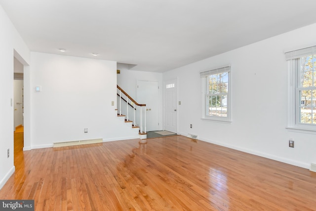 unfurnished living room featuring a baseboard radiator and light hardwood / wood-style flooring