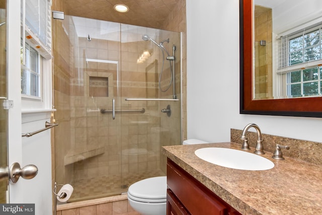 bathroom with a shower with door, vanity, and toilet