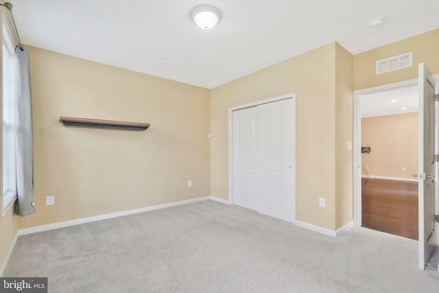 unfurnished bedroom featuring a closet and light carpet