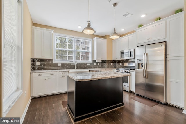 kitchen with white cabinetry, decorative backsplash, stainless steel appliances, and decorative light fixtures