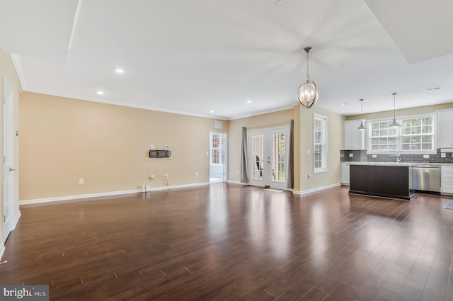 unfurnished living room with ornamental molding, dark hardwood / wood-style flooring, a notable chandelier, and sink