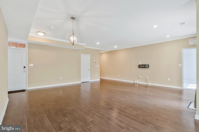 spare room with dark hardwood / wood-style flooring, a notable chandelier, and ornamental molding