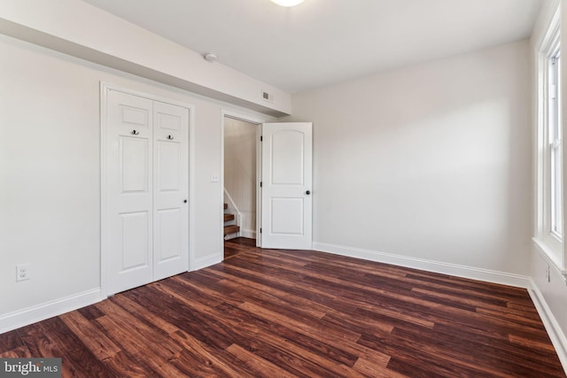 unfurnished bedroom with multiple windows and dark hardwood / wood-style floors