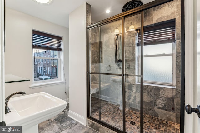 bathroom featuring a shower with shower door and sink