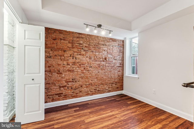 spare room with dark hardwood / wood-style floors and brick wall