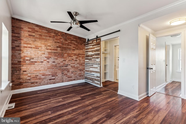 unfurnished bedroom featuring a barn door, ceiling fan, crown molding, dark hardwood / wood-style floors, and brick wall