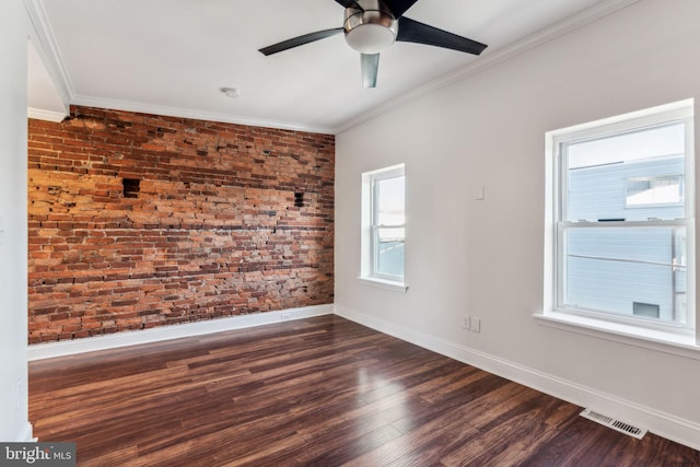 spare room featuring ceiling fan, a healthy amount of sunlight, brick wall, and dark hardwood / wood-style flooring