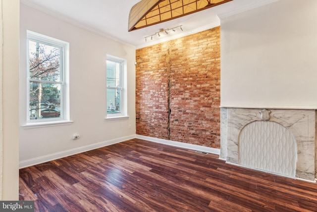 unfurnished living room featuring dark hardwood / wood-style flooring, brick wall, and crown molding