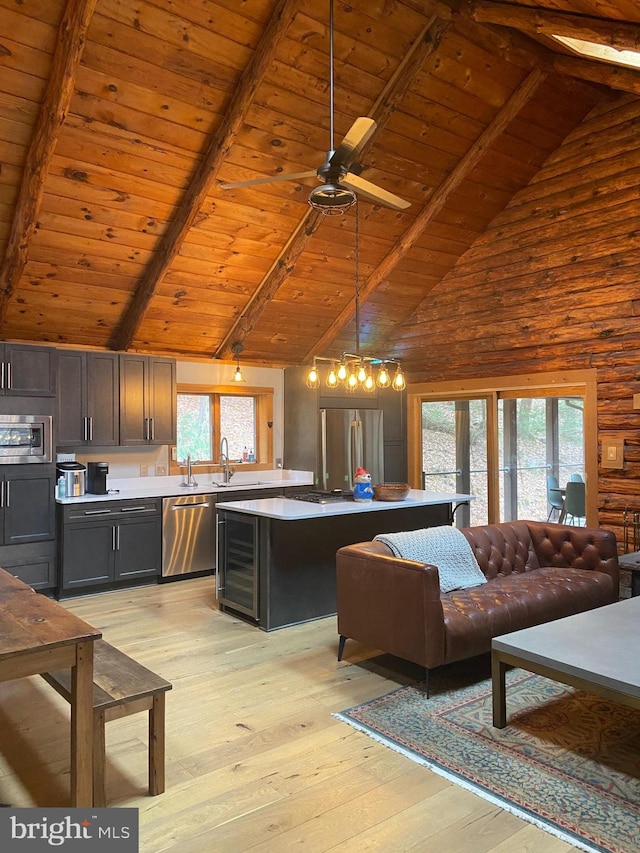 kitchen featuring appliances with stainless steel finishes, light wood-type flooring, decorative light fixtures, high vaulted ceiling, and beamed ceiling