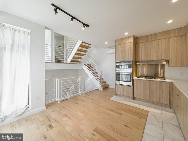 1607 Germantown Ave, Philadelphia, PA 19122 - kitchen with stainless steel appliances, light brown cabinets, light wood-style flooring, a wall mounted AC, and under cabinet range hood