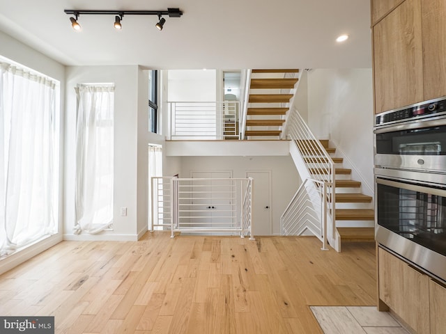 unfurnished living room featuring track lighting and light hardwood / wood-style flooring