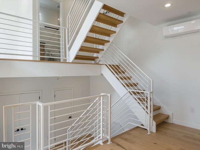 stairway featuring wood-type flooring and an AC wall unit