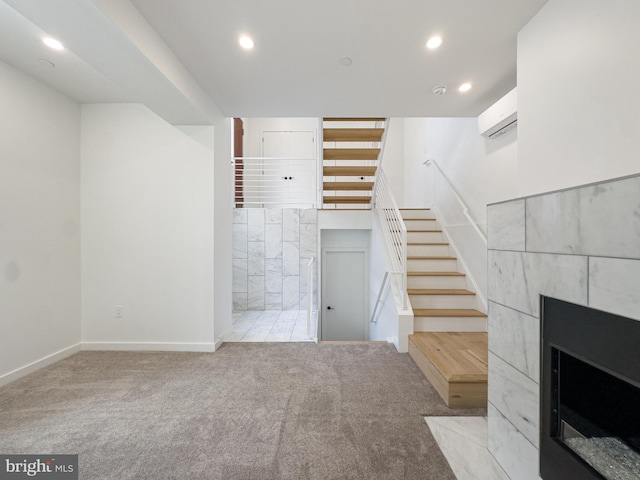 unfurnished living room with a tiled fireplace, light colored carpet, and a wall mounted AC