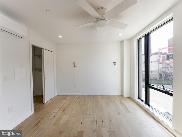 spare room with ceiling fan, light hardwood / wood-style floors, and a wall mounted AC