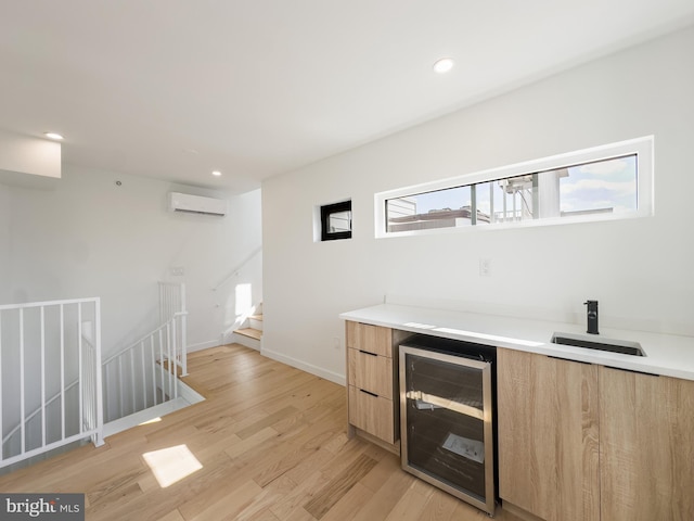 bar with beverage cooler, sink, light wood-type flooring, and a wall mounted air conditioner