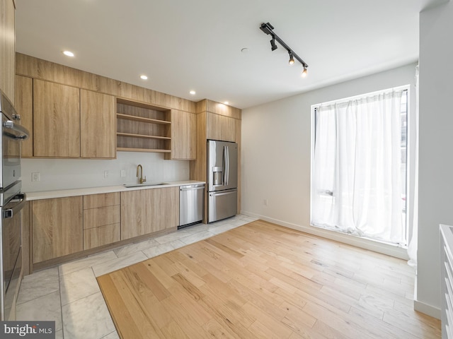 kitchen with stainless steel appliances, light hardwood / wood-style floors, sink, and track lighting