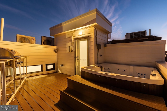 deck at dusk with an outdoor hot tub