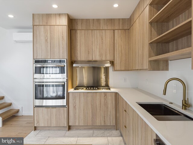 kitchen with light hardwood / wood-style floors, sink, appliances with stainless steel finishes, light brown cabinetry, and an AC wall unit