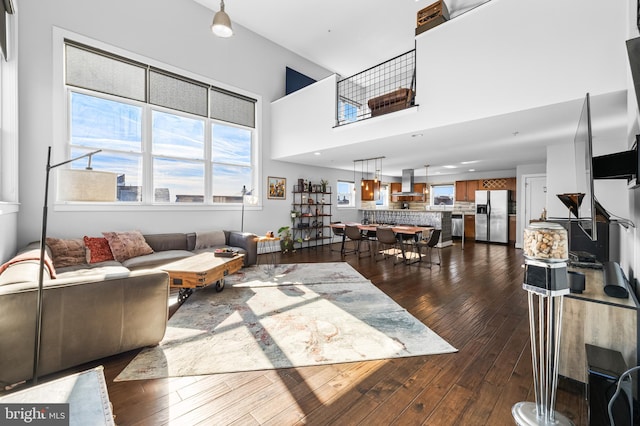 living room featuring a towering ceiling and dark wood-type flooring