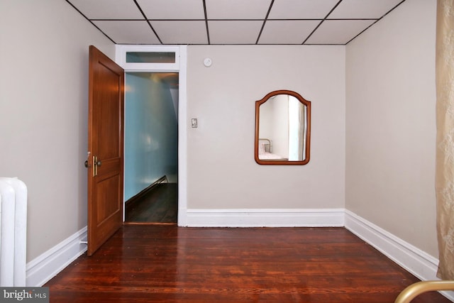 spare room with dark hardwood / wood-style flooring, radiator, and a paneled ceiling