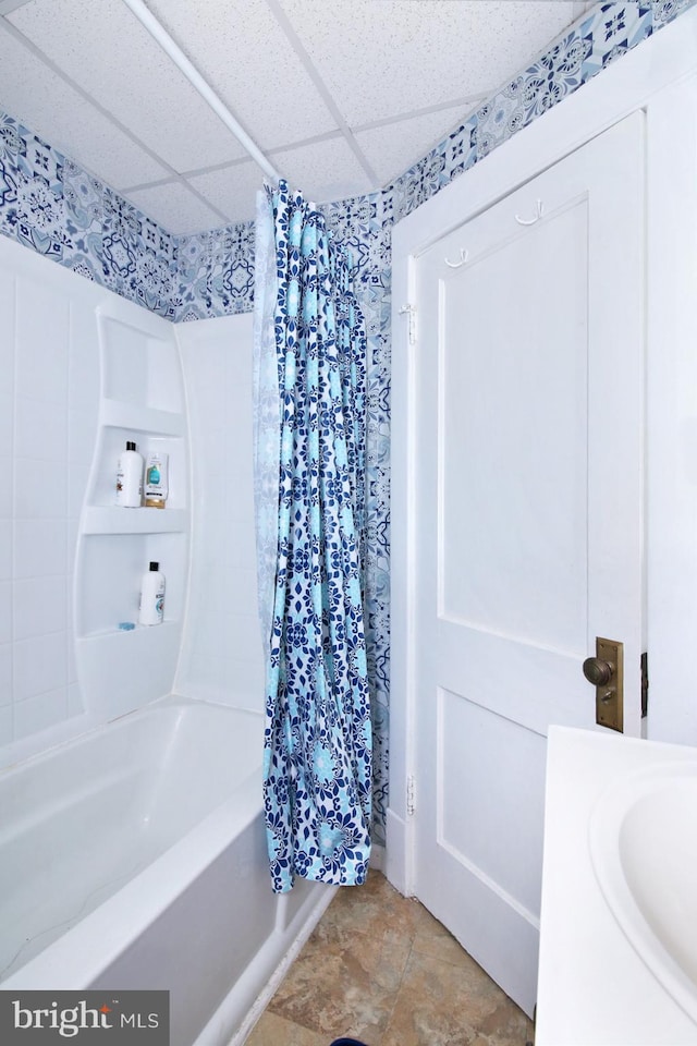 bathroom featuring a paneled ceiling and shower / bathtub combination with curtain