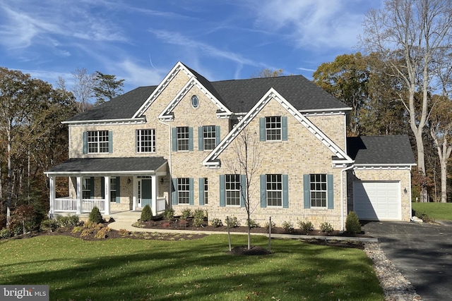 view of front of property with a front lawn, covered porch, and a garage