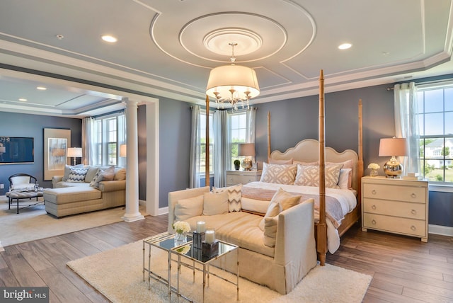 bedroom featuring wood-type flooring, a tray ceiling, and multiple windows