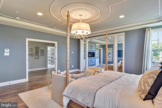 bedroom featuring a notable chandelier, crown molding, ornate columns, and dark wood-type flooring