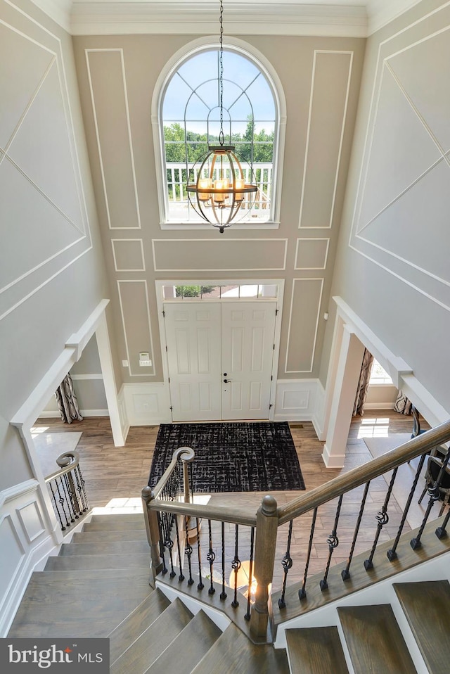 entrance foyer with wood-type flooring, ornamental molding, and a notable chandelier