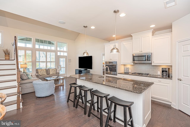 kitchen featuring a kitchen island with sink, white cabinets, dark wood-type flooring, and appliances with stainless steel finishes