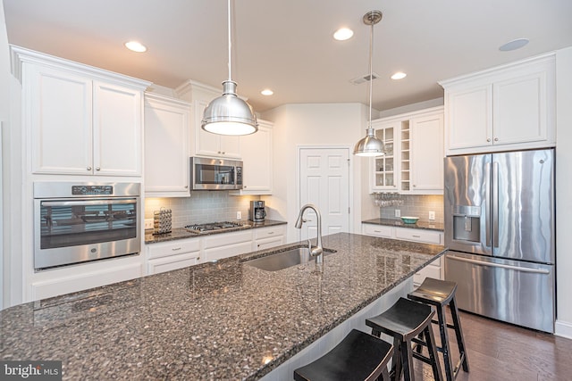 kitchen with decorative light fixtures, stainless steel appliances, white cabinetry, and sink