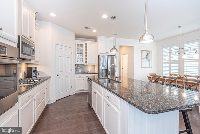 kitchen with stainless steel appliances, sink, dark hardwood / wood-style floors, white cabinetry, and an island with sink