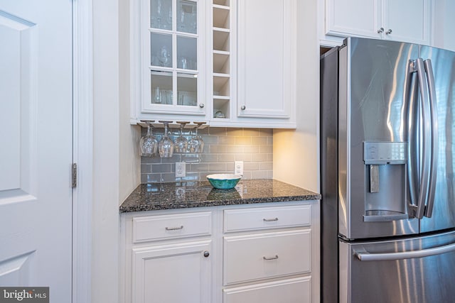 kitchen featuring tasteful backsplash, white cabinetry, dark stone counters, and stainless steel refrigerator with ice dispenser