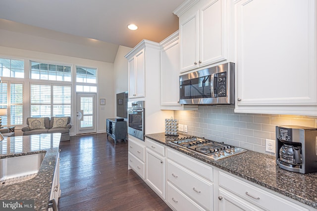 kitchen featuring tasteful backsplash, stainless steel appliances, dark wood-type flooring, dark stone countertops, and white cabinets