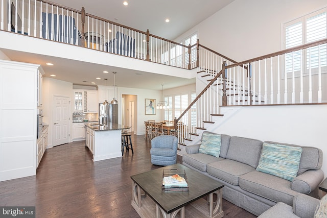 living room featuring a notable chandelier, dark hardwood / wood-style flooring, sink, and a high ceiling