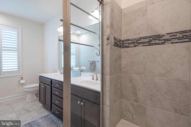 bathroom featuring a tile shower, vanity, and toilet