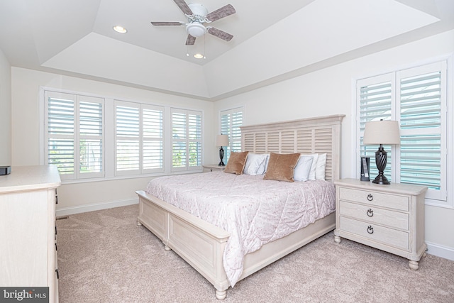 bedroom featuring light carpet, a raised ceiling, and ceiling fan