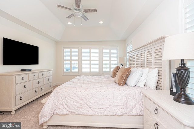 carpeted bedroom with ceiling fan and a tray ceiling