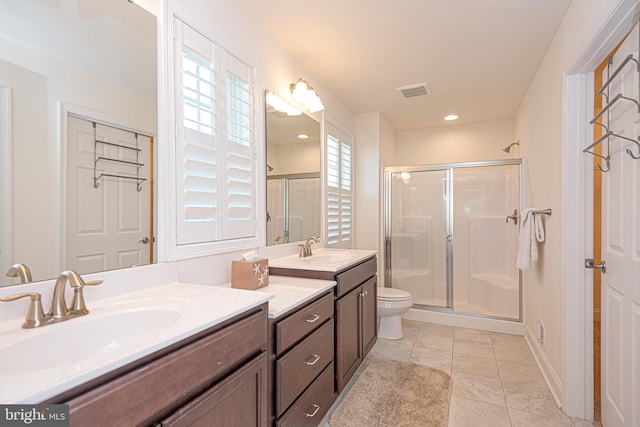 bathroom with vanity, toilet, a shower with shower door, and a wealth of natural light