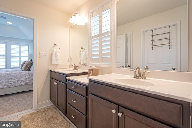 bathroom with tile patterned floors, vanity, a healthy amount of sunlight, and lofted ceiling