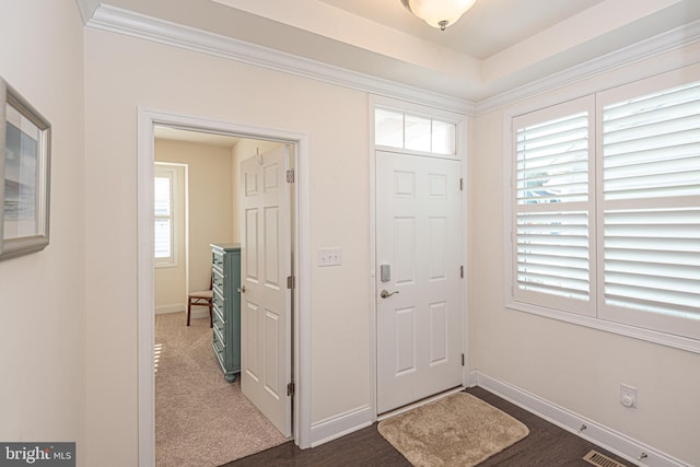 foyer entrance with plenty of natural light, ornamental molding, and dark wood-type flooring