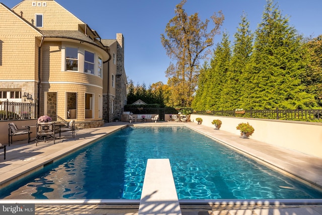 view of pool featuring a patio area and a diving board