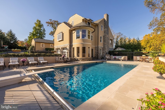 view of pool with a patio area and a diving board