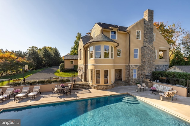 rear view of house with a fenced in pool, outdoor lounge area, and a patio