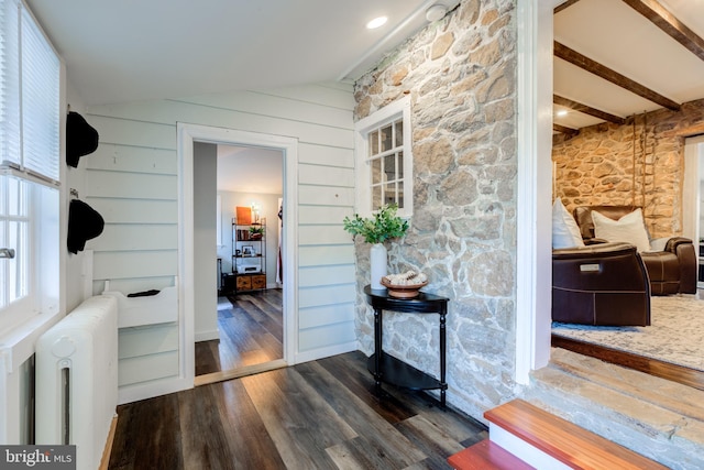 hall with radiator, wood walls, dark wood-type flooring, and vaulted ceiling